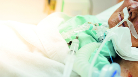 Mann im Krankenbett wird intensivmedizinisch betreut