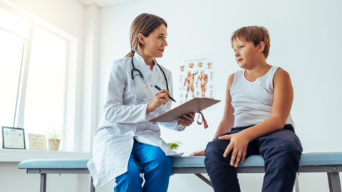 Kinderärztin untersucht ein Kind im Grundschulalter