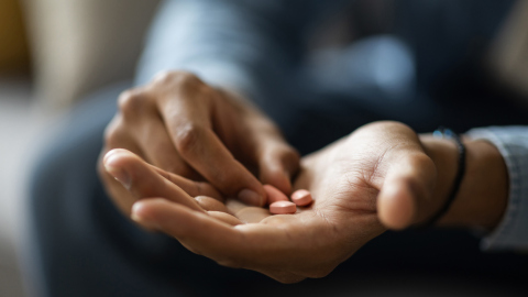 Hände eines Mannes mit Tabletten in der Hand
